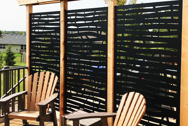 2 chairs with black aluminum privacy screens with abstract patterns with wooden frames in the background.